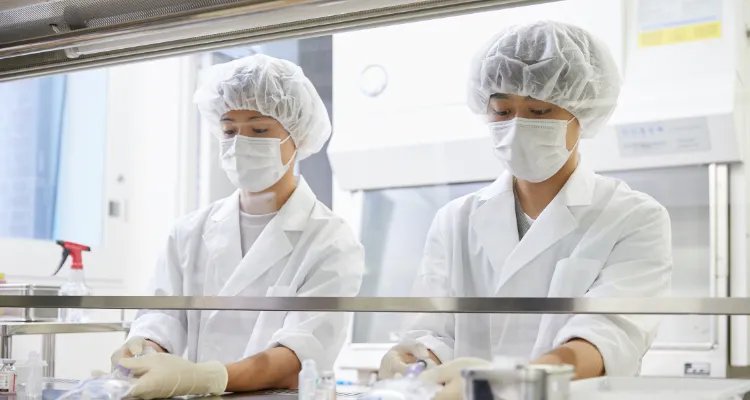 写真:白衣、マスク、ヘアキャップ、手袋をつけて研究している生徒たち